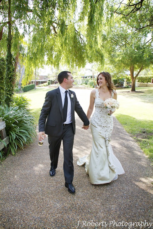 Bride and groom walking a long path at garden wedding reception - wedding photography sydney